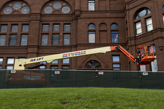 A piece of construction equipment is parked beside Crouse College as work continues on masonry restoration to the building's bell tower and building cupolas. Photo taken by July 11, 2017