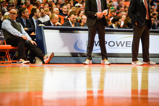 The coaches align the sideline, all wearing matching sneakers.