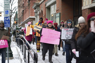 Bundled against the extreme cold, protesters bear signs advocating for gender equality as they march. 